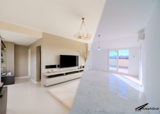 Interior de un salón moderno, con áreas claras y luminosas, y un televisor en la pared.